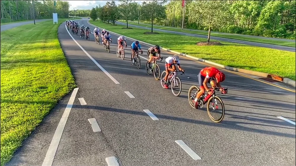 A pack of road cyclists racing in formation down a tree-lined Jacksonville road