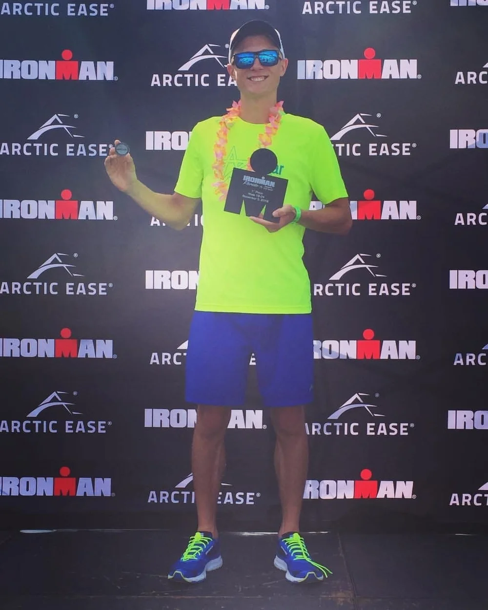 An IRONMAN athlete in front of the IRONMAN awards backdrop