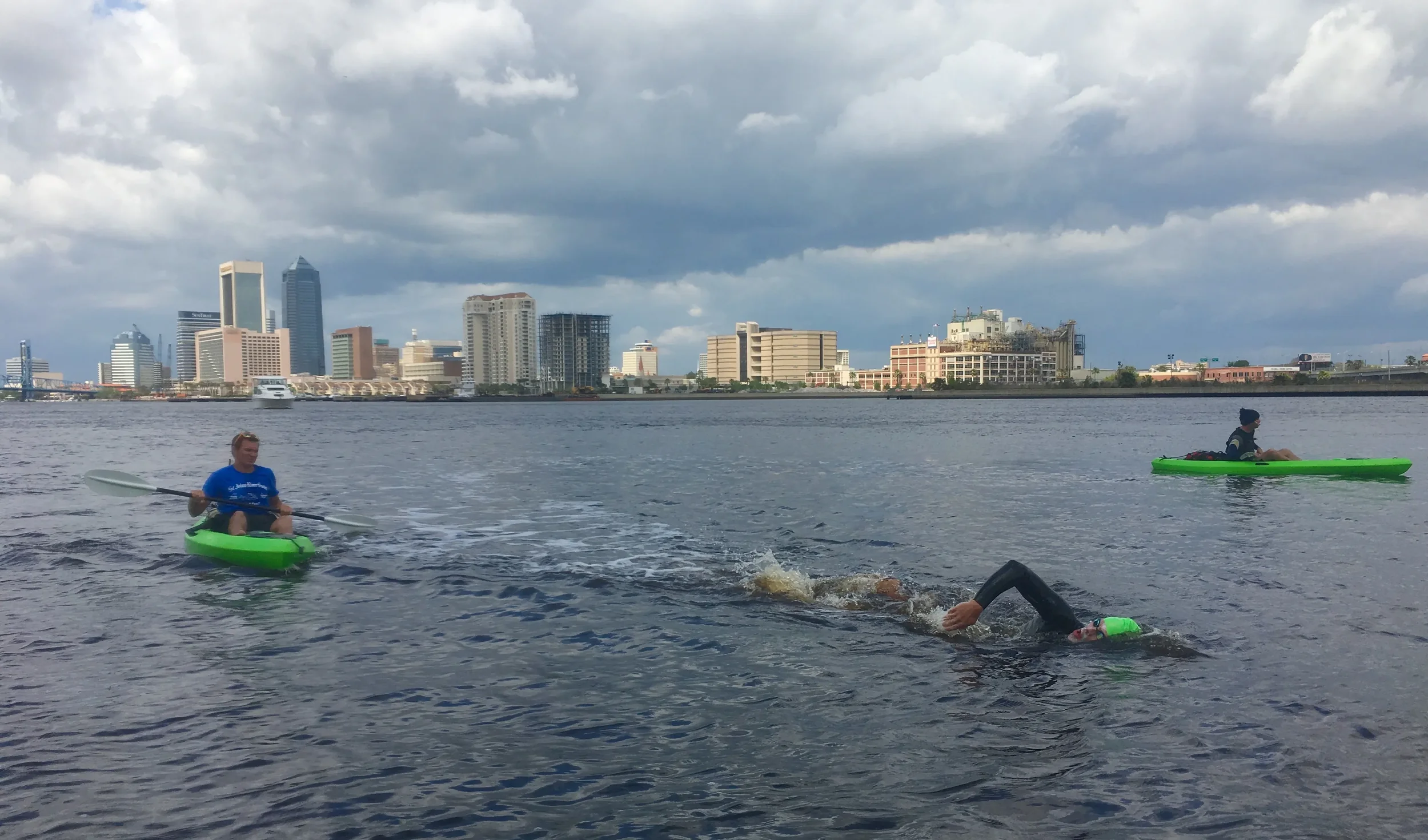 Open-water swimmers in the St. Johns River with the Jacksonville skyline behind them